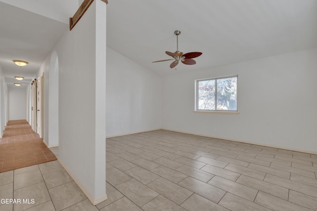 empty room with light tile patterned floors, a ceiling fan, and vaulted ceiling