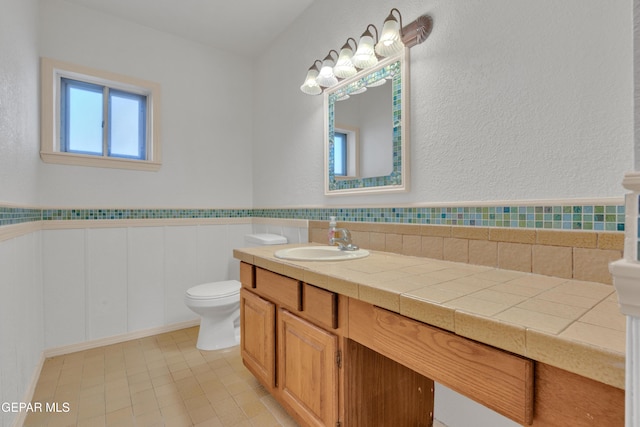 bathroom with vanity, toilet, and wainscoting