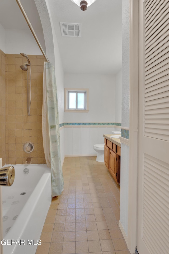 full bath with vanity, shower / bathtub combination with curtain, a wainscoted wall, visible vents, and toilet