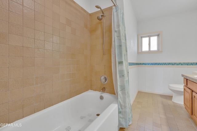 bathroom with vanity, toilet, shower / bathtub combination with curtain, and wainscoting