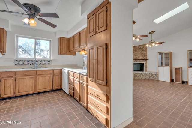 kitchen with lofted ceiling with skylight, a sink, open floor plan, a fireplace, and light countertops