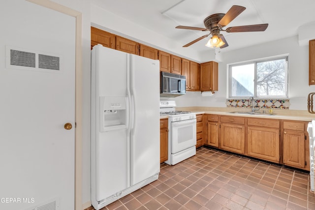 kitchen featuring visible vents, a sink, white appliances, light countertops, and ceiling fan