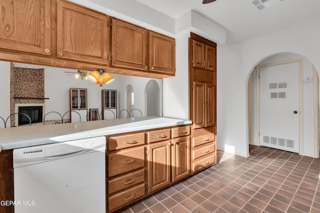 kitchen featuring visible vents, a large fireplace, ceiling fan, and white dishwasher