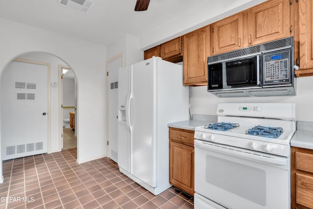 kitchen with visible vents, white appliances, arched walkways, and light countertops