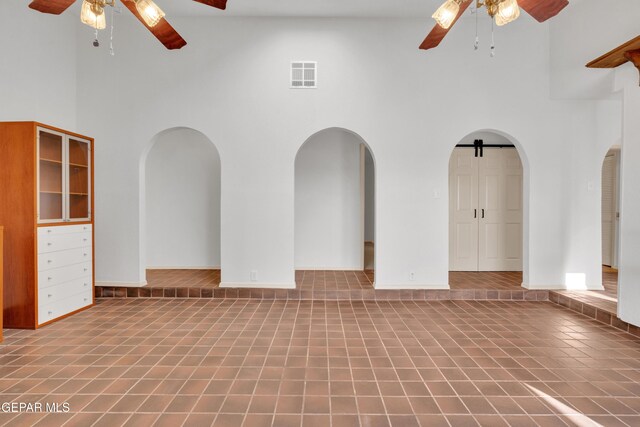 tiled spare room with a high ceiling, arched walkways, and ceiling fan