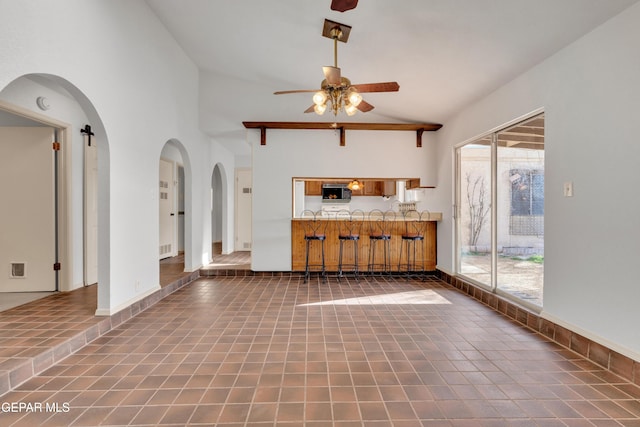 unfurnished living room featuring visible vents, baseboards, arched walkways, tile patterned floors, and a ceiling fan