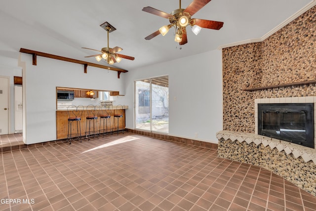 unfurnished living room featuring lofted ceiling, a tiled fireplace, tile patterned flooring, baseboards, and ceiling fan