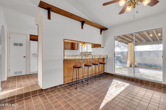 kitchen with tile patterned floors, visible vents, open shelves, white fridge with ice dispenser, and vaulted ceiling with beams