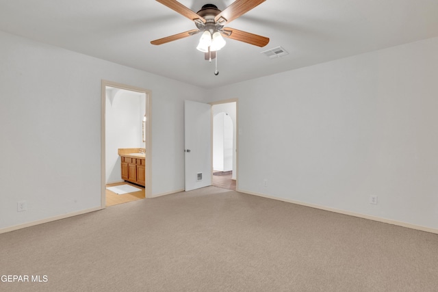 unfurnished bedroom featuring visible vents, light carpet, ensuite bathroom, arched walkways, and baseboards