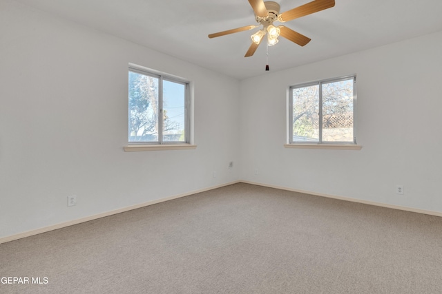 carpeted spare room featuring baseboards, plenty of natural light, and ceiling fan