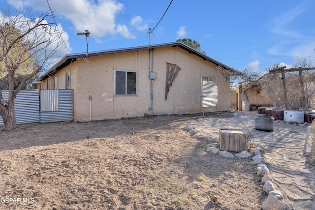 back of property featuring stucco siding and fence