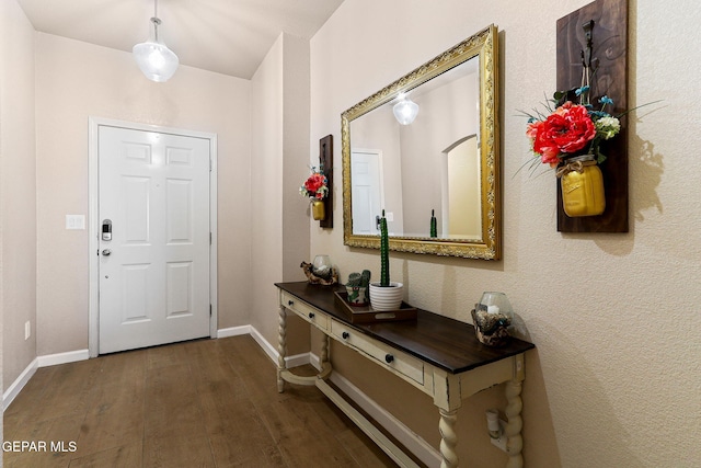 foyer featuring dark wood finished floors and baseboards