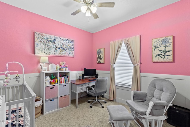 carpeted office featuring a ceiling fan and wainscoting