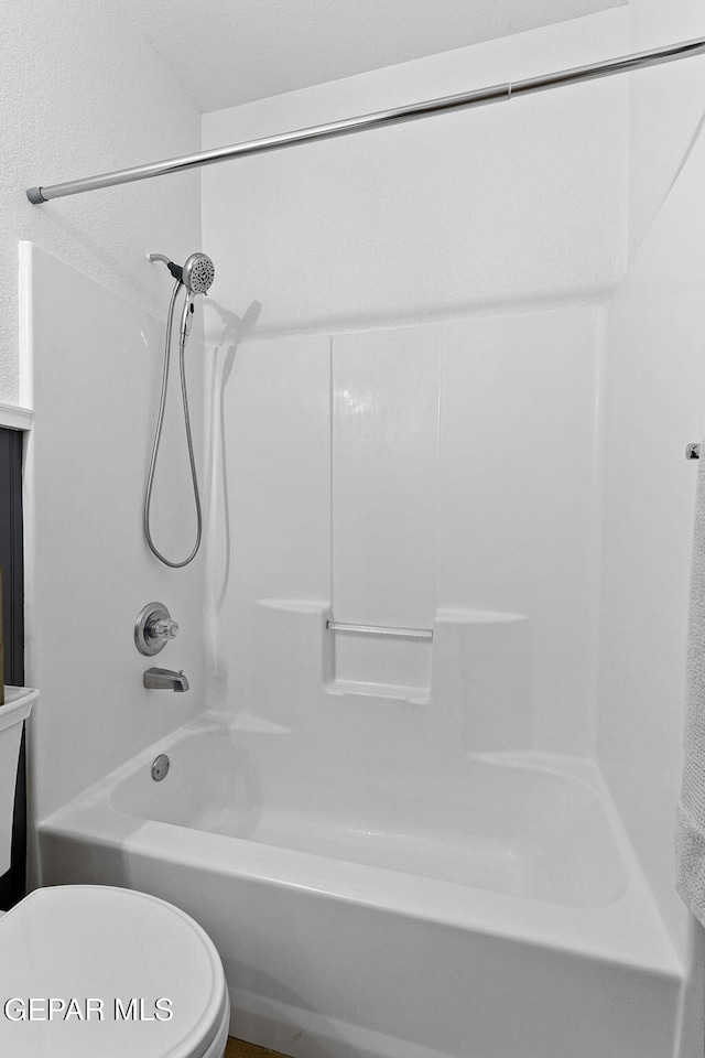 bathroom with bathing tub / shower combination and toilet