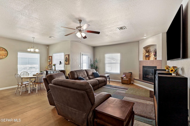 living room featuring light wood-style flooring, a healthy amount of sunlight, visible vents, and a tile fireplace