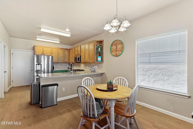 kitchen featuring visible vents, a peninsula, light wood-style flooring, stainless steel appliances, and backsplash