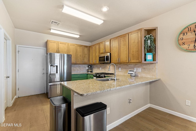 kitchen featuring tasteful backsplash, visible vents, a peninsula, stainless steel appliances, and a sink