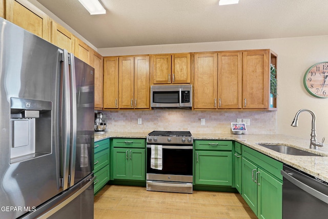 kitchen featuring light wood finished floors, tasteful backsplash, appliances with stainless steel finishes, and a sink