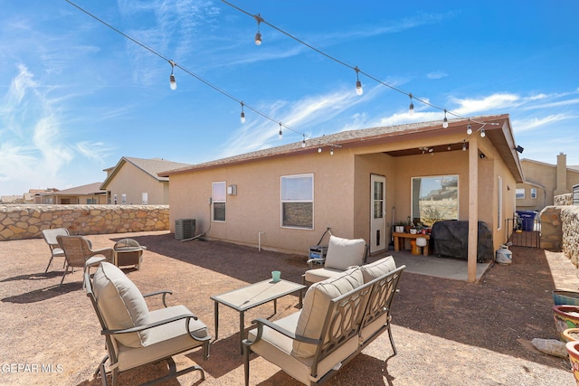 rear view of house featuring a patio, cooling unit, fence, stucco siding, and an outdoor living space with a fire pit