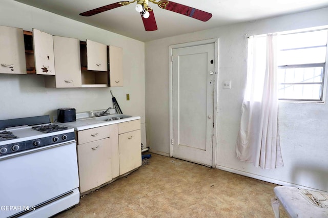 kitchen with a ceiling fan, light floors, light countertops, white cabinets, and white gas range oven