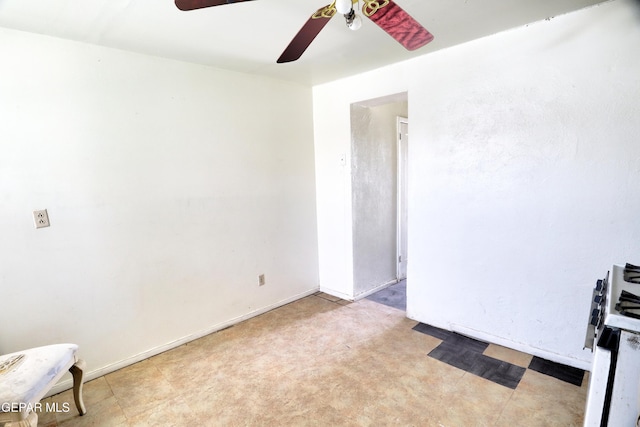 empty room with a ceiling fan and baseboards