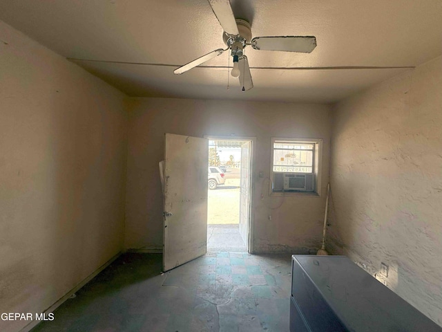 interior space featuring cooling unit, ceiling fan, and a textured wall