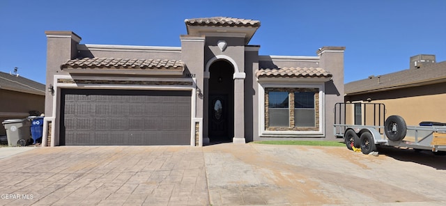 mediterranean / spanish house featuring decorative driveway, a garage, and stucco siding