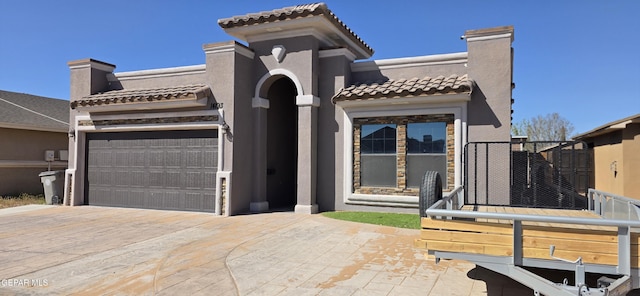 mediterranean / spanish-style home featuring stucco siding, driveway, a tile roof, and a garage