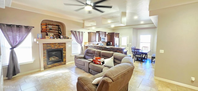 living room featuring a wealth of natural light, a stone fireplace, and baseboards