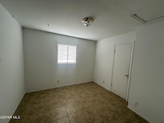 spare room featuring baseboards, a textured ceiling, and tile patterned flooring