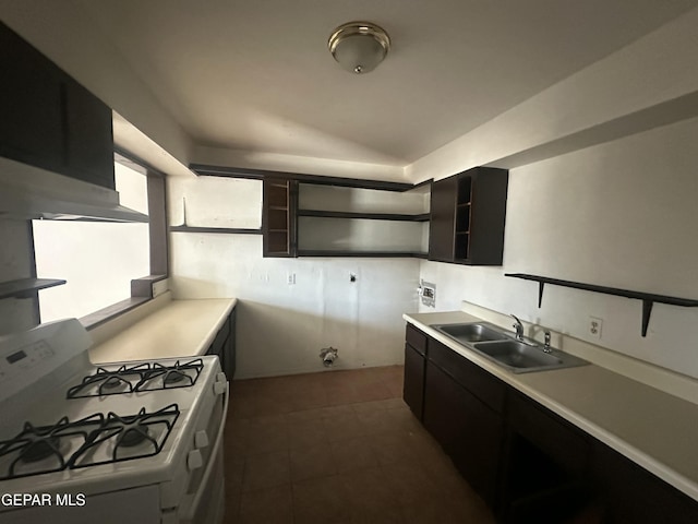 kitchen featuring light countertops, white gas stove, open shelves, and a sink