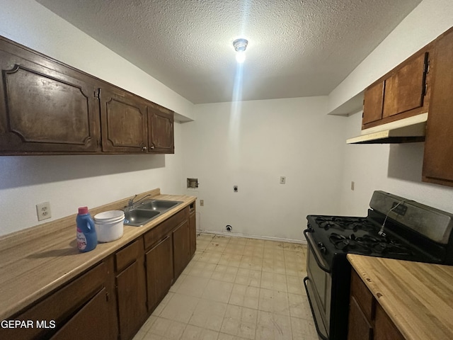 kitchen featuring light floors, black gas stove, a sink, light countertops, and under cabinet range hood