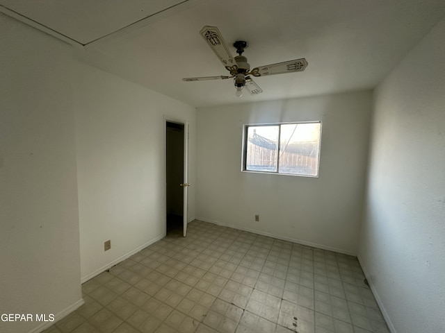 spare room with baseboards, light floors, and a ceiling fan