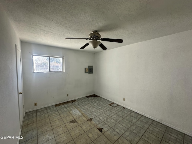 empty room featuring a textured ceiling, tile patterned floors, electric panel, and ceiling fan