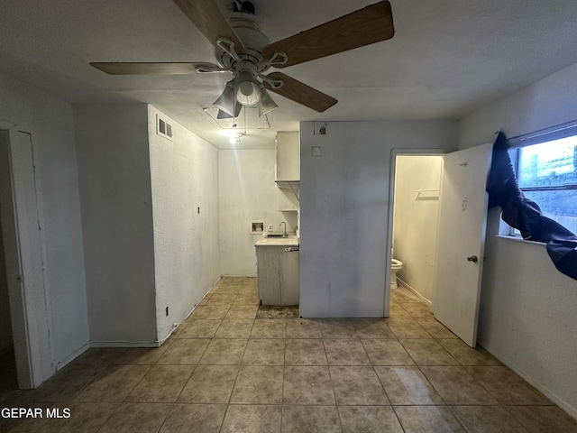 kitchen with light tile patterned floors, a ceiling fan, visible vents, a sink, and light countertops