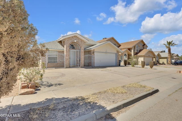 view of front of home with brick siding, an attached garage, driveway, and fence