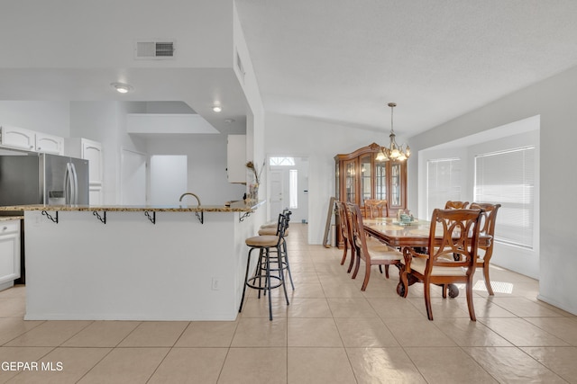 dining space featuring light tile patterned flooring, visible vents, and a chandelier