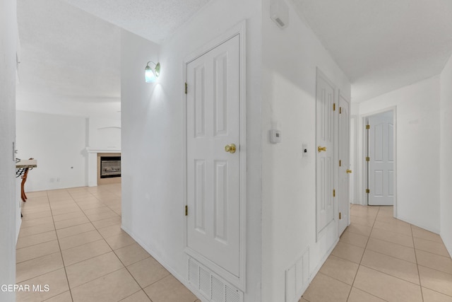 corridor featuring a textured ceiling and light tile patterned flooring