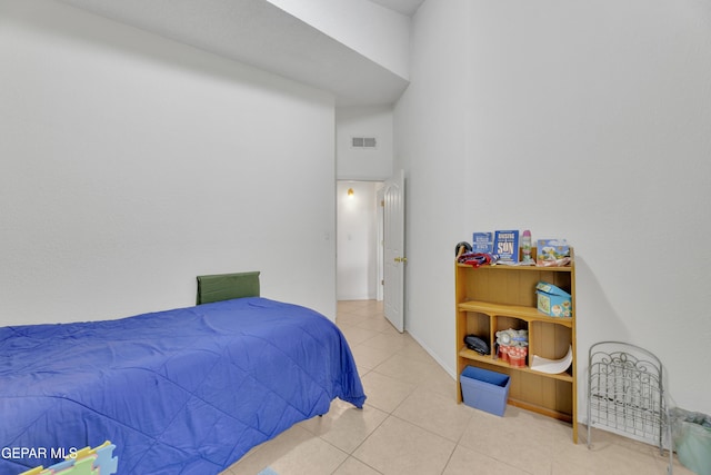 bedroom featuring tile patterned flooring, visible vents, and a high ceiling