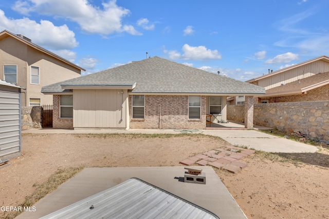 rear view of property with a patio, brick siding, fence private yard, and a shingled roof