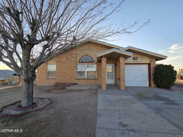 ranch-style house with driveway, brick siding, and an attached garage