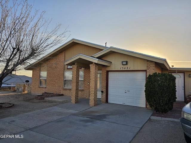 view of front facade with driveway, brick siding, and an attached garage