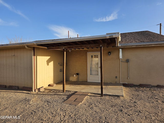 rear view of property with a shingled roof and a patio area