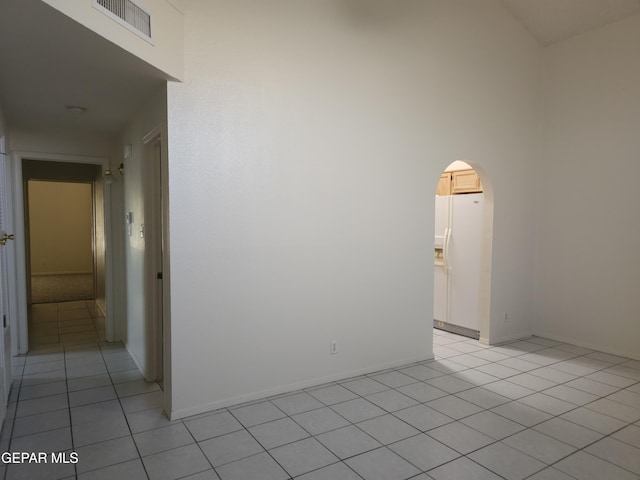 spare room featuring visible vents, arched walkways, baseboards, and light tile patterned flooring