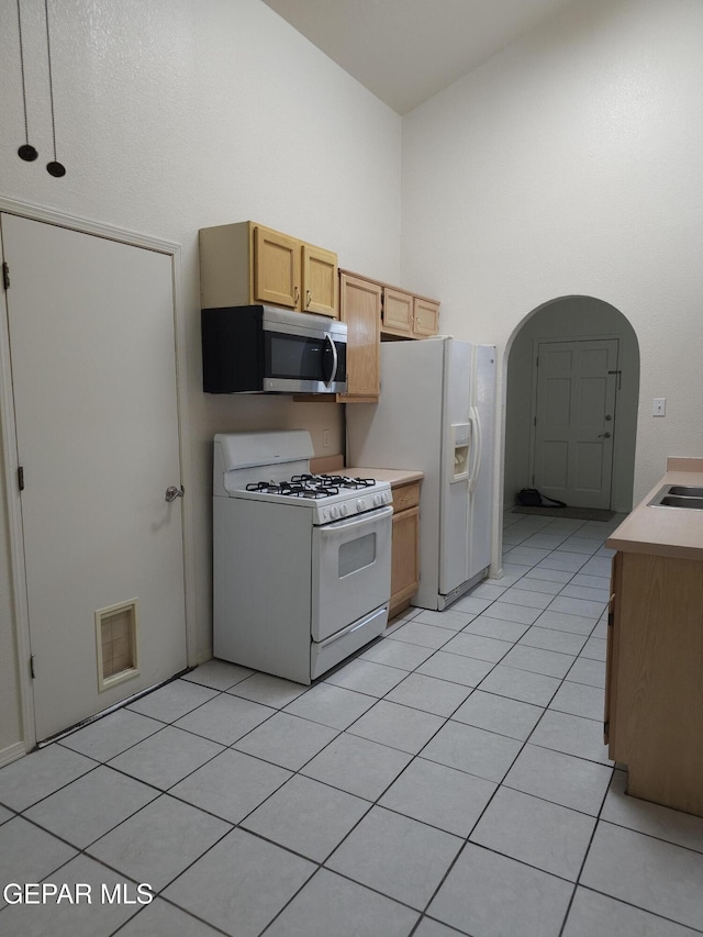 kitchen with white appliances, visible vents, light tile patterned flooring, light countertops, and a towering ceiling