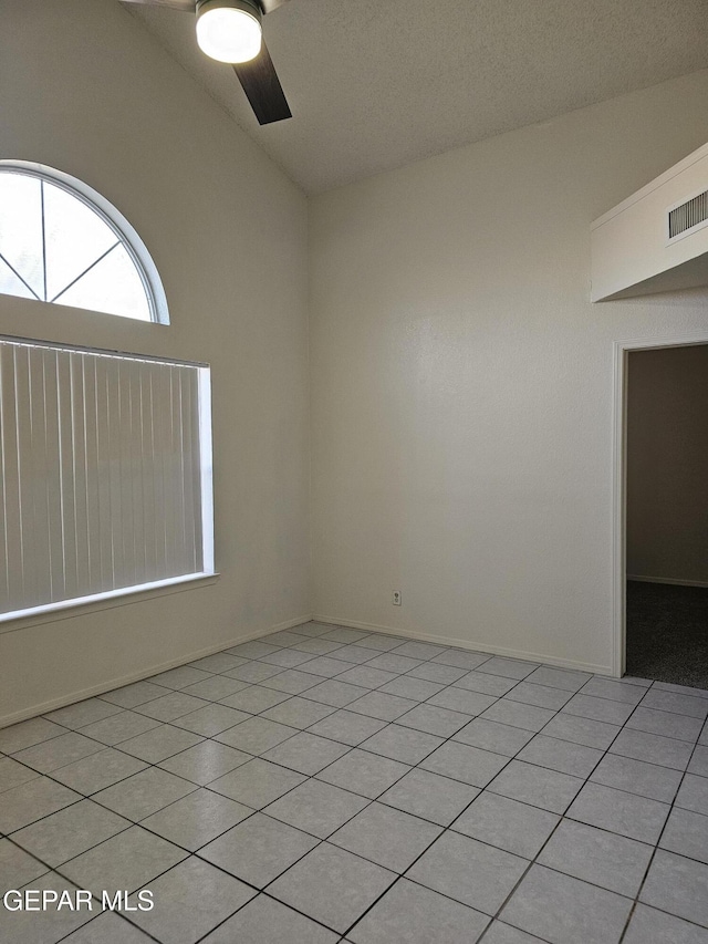 empty room with light tile patterned floors, visible vents, lofted ceiling, and a ceiling fan