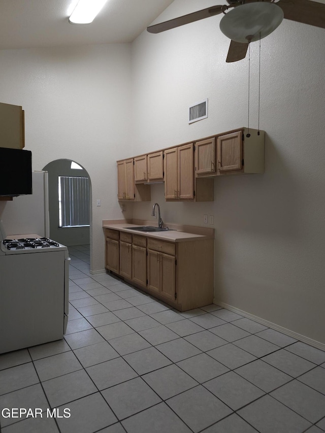 kitchen featuring visible vents, light countertops, range with gas stovetop, arched walkways, and a sink