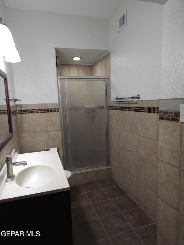 bathroom with vanity, visible vents, a stall shower, tile walls, and tile patterned floors