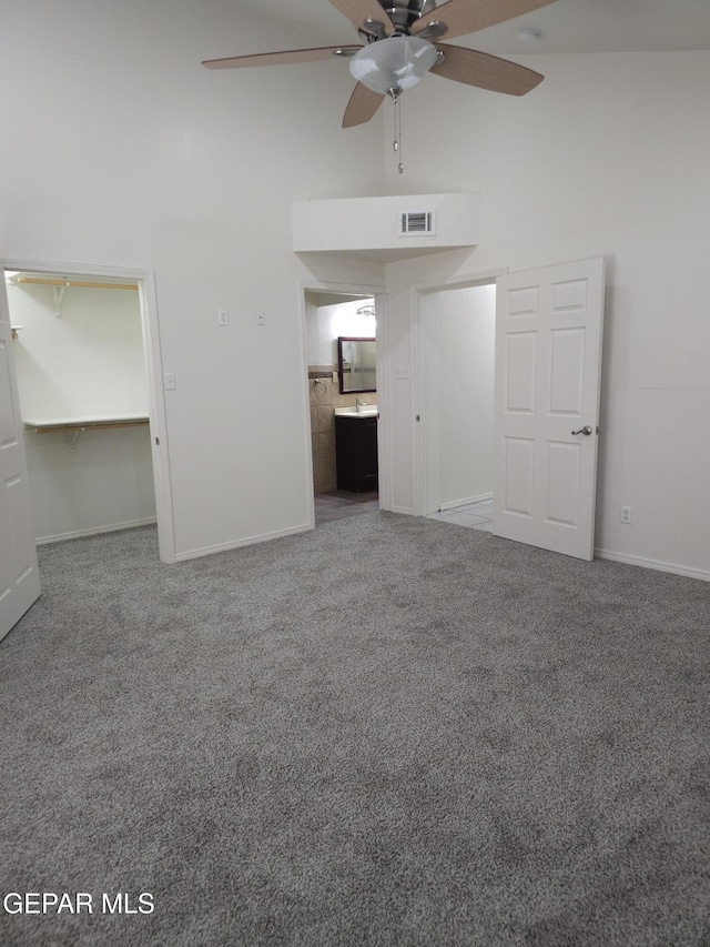 interior space featuring visible vents, ceiling fan, baseboards, and a towering ceiling