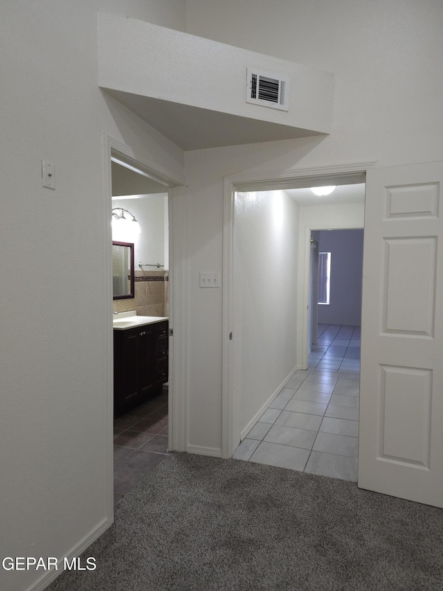 corridor with light tile patterned floors, visible vents, and light carpet